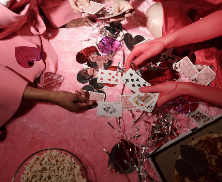 Women playing cards together at a festive table, symbolizing connection, laughter, and female friendship